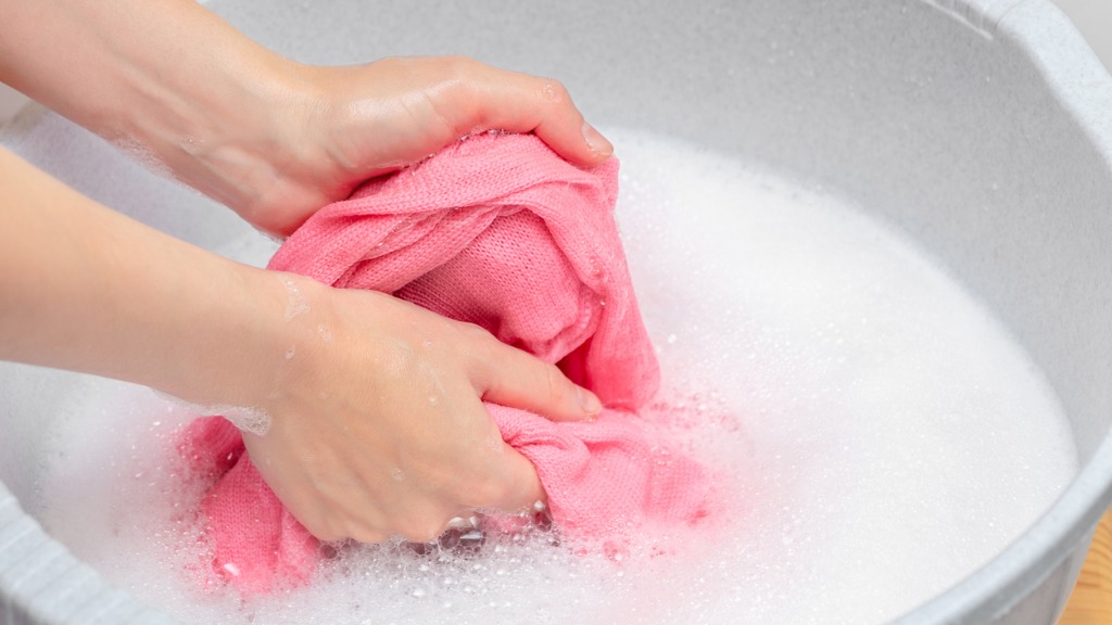 Woman hand washing knitted woolen laundry in grey plastic basinlot of picture id1017857886